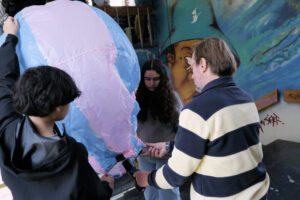 Une montgolfière artisanale flotte dans une cage d’escalier ornée de graffitis, pendant qu’un animateur la guide.