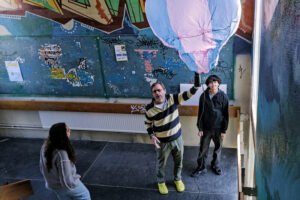 Une montgolfière artisanale flotte dans une cage d’escalier ornée de graffitis, pendant qu’un animateur la guide.