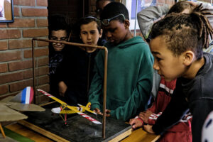 Des enfants autour d’un simulateur de vol en bois.
